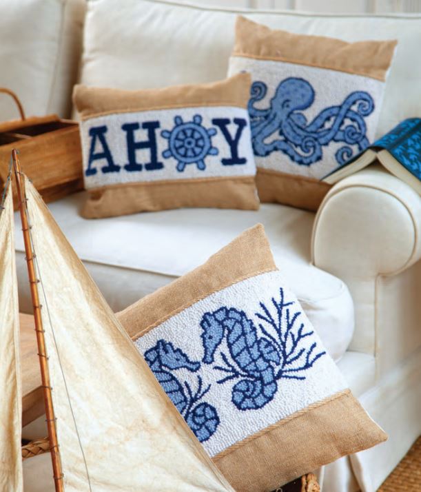 Three Burlap and Hook Pillows. One pillow says Ahoy on it with an anchor, the second has a blue octopus and the third pillow has blue seahorses with a little bit of coral on it.
