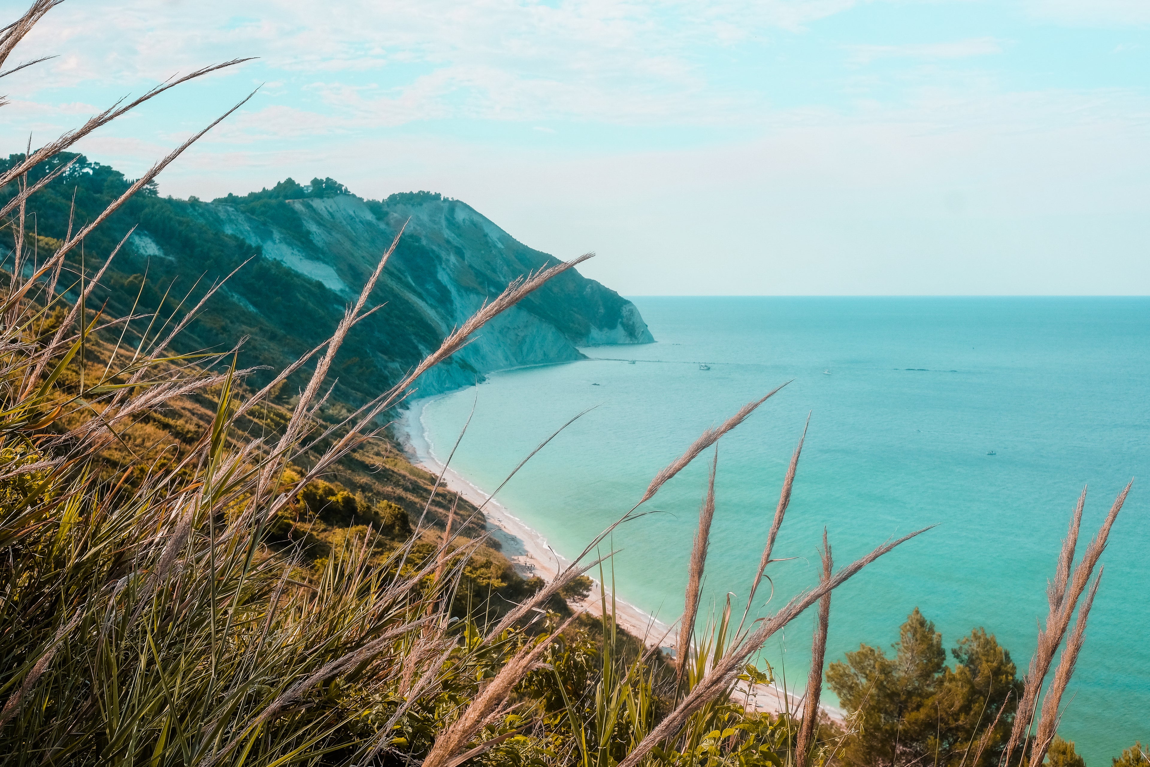 Coastal view with cliffs on the left, a sliver of beach and aqua sea to the right